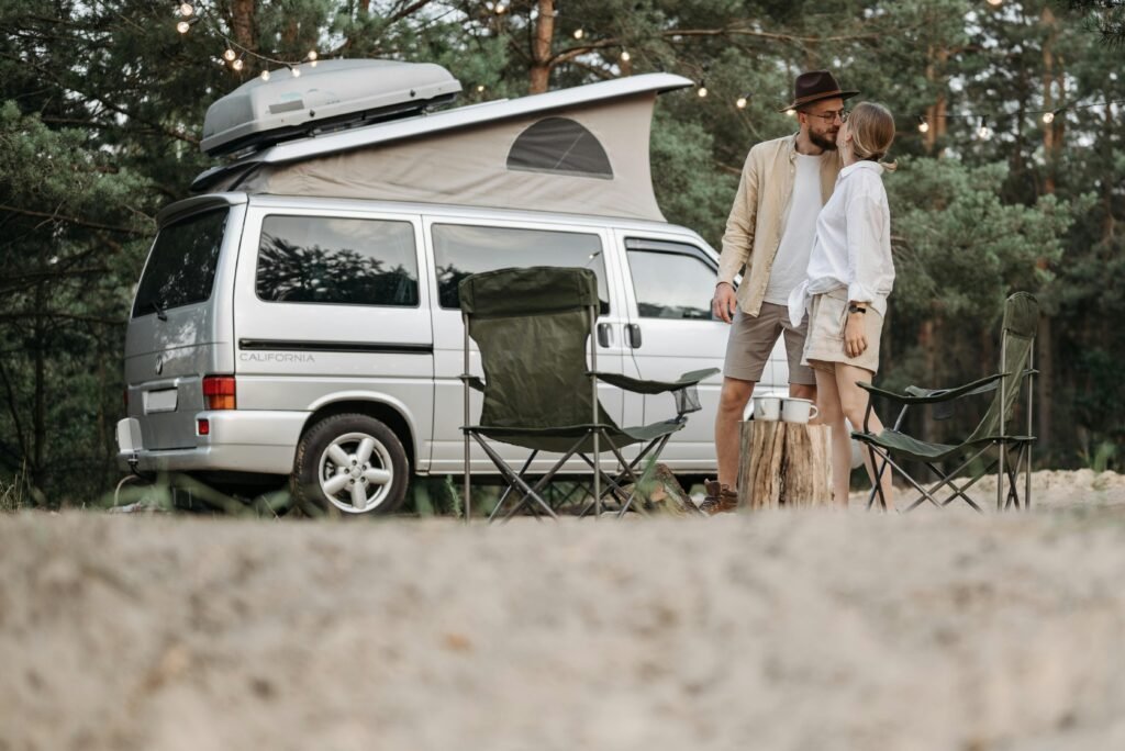 A couple shares a romantic moment by their camper van in a serene outdoor setting.