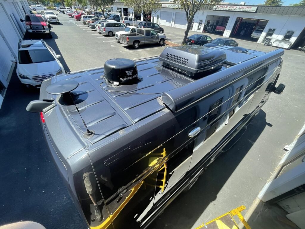 Winegard RV internet antenna mounted on top of a Class C motorhome parked at an outdoor campsite