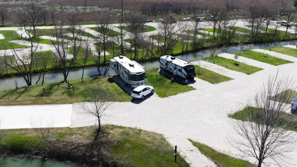 Aerial view of two RVs parked at best RV parks in Texas gravel campsites alongside a narrow creek at Long Creek RV Park.