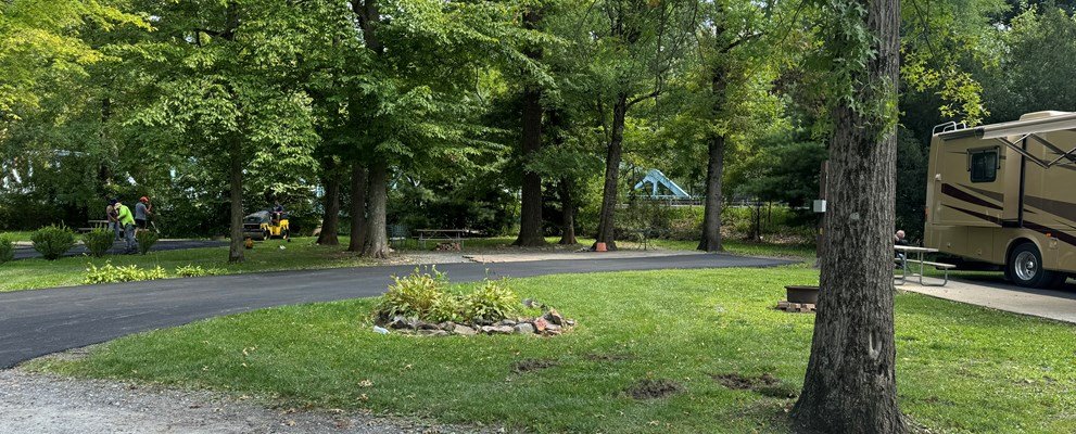 Wooded full-hookup campsite surrounded by mature trees at Jonestown Hershey NE KOA Journey near Hershey, PA