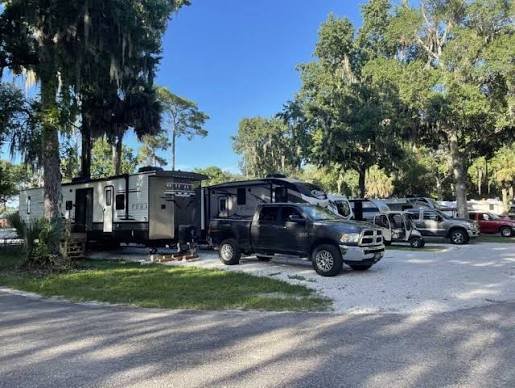 Class A motorhome parked at a paved campsite with full hookups and lush trees at a Florida RV resort