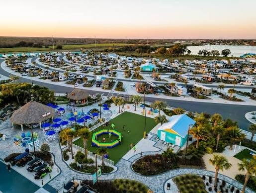 Camp Margaritaville RV Resort Auburndale aerial view with paved campsites, water slide, pool area, and palm trees in Florida