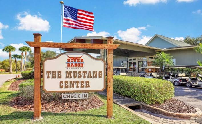 The Mustang Center check-in hub and welcome office under a blue sky at River Ranch RV Resort in Florida